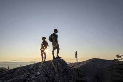 Rear view of people standing on rock against sky