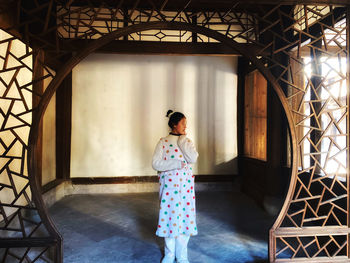 Rear view of young woman standing by window