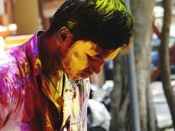 Side view of young man face covered with colorful powder paints 