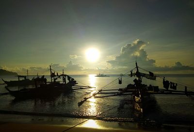 Silhouette of fishing net on sea against sky during sunset