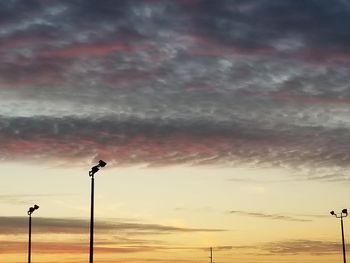 Low angle view of silhouette street light against dramatic sky