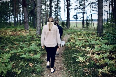 Rear view of women walking the dog in forest