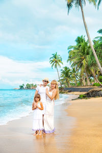 Portrait of parents with girl by seashore at beach