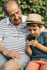 Mature man using smart phone while sitting on laptop