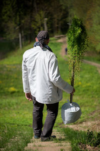 Man holding plants while walking on field