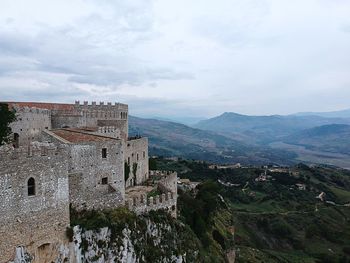 Old building by mountain against sky