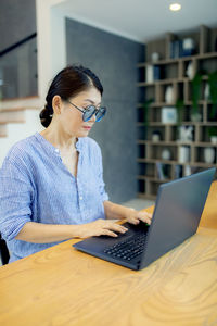 Woman using mobile phone while sitting on table