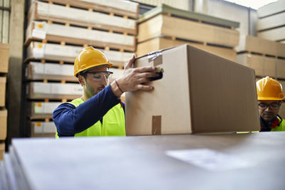 Worker carrying box in factory warehouse