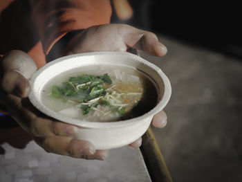 Close-up of hand holding bowl of soup