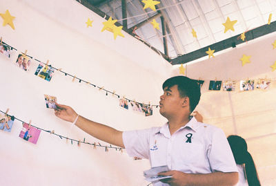 Portrait of young man standing against ceiling