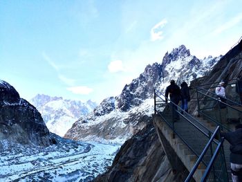 Low angle view of people on staircase by snowcapped mountain against sky