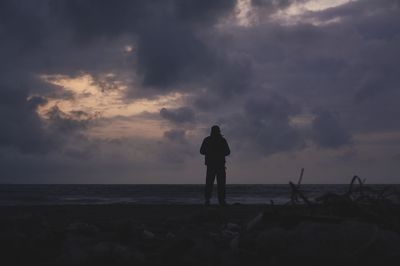 Silhouette man standing on beach against sky during sunset