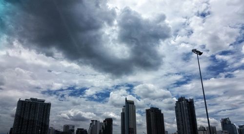 Low angle view of skyscrapers against cloudy sky