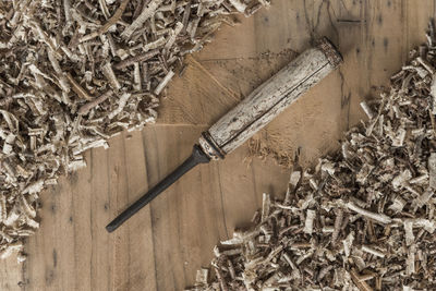 Directly above shot of chisel and wood shavings on table