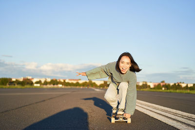Portrait of young woman walking on road against clear sky