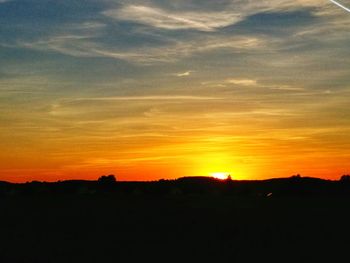 Silhouette landscape against dramatic sky during sunset