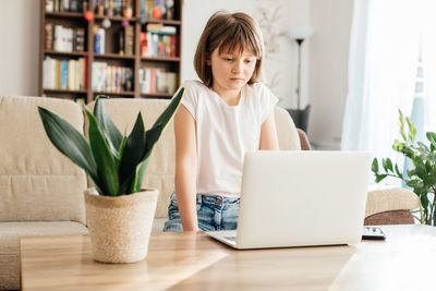 Distance learning. the girl sits at home on the couch and studies using a laptop or makes calls 