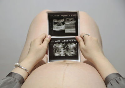 Midsection of pregnant woman holding ultrsound result