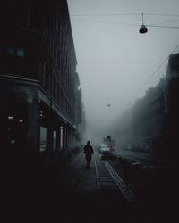 Man walking on road amidst buildings in city