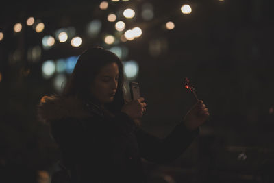 Young woman photographing food at night
