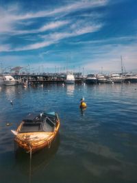 Boats moored at harbor against sky