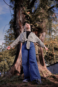 Portrait of women standing by tree trunk in forest