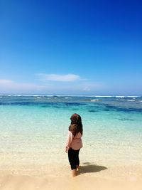 Woman wearing hijab while standing on beach against sky