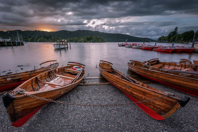 Boats moored in sea against cloudy sky