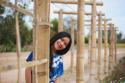 Portrait of smiling young woman by bamboo built structure
