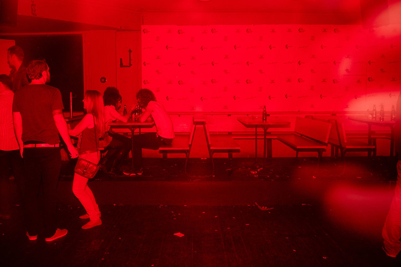 PEOPLE SITTING ON RED STAGE AT BAR