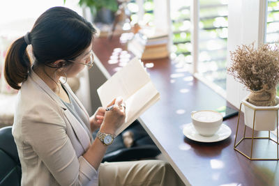 Side view of woman using digital tablet while sitting on table