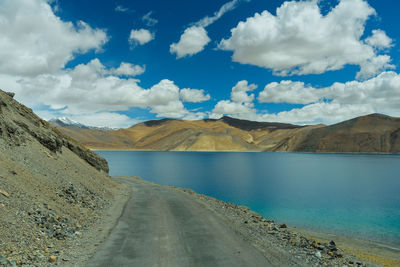 Scenic view of road by mountains against sky