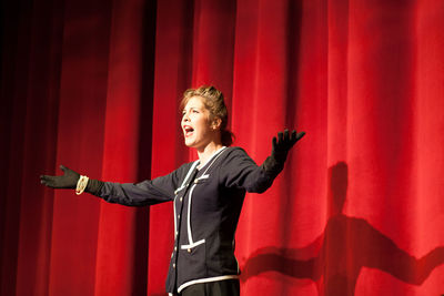 Actress by red curtain performing