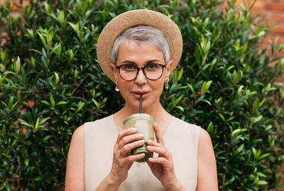 Portrait of young woman drinking water in park