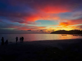 Silhouette people on beach against sky during sunset