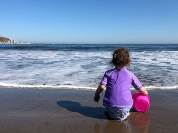 Rear view of woman looking at sea against clear sky