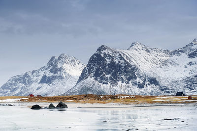 Scenic view of sea by snowcapped mountain against sky