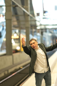 Thoughtful businessman gesturing at railroad station platform