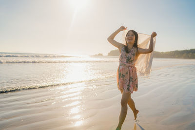 Woman standing at beach against sky