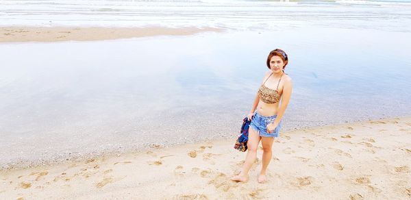 Full length of young woman standing at beach