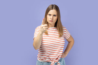 Portrait of young woman using mobile phone against blue background