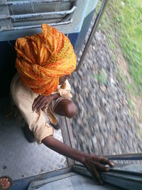 High angle view of senior man crouching at door in train