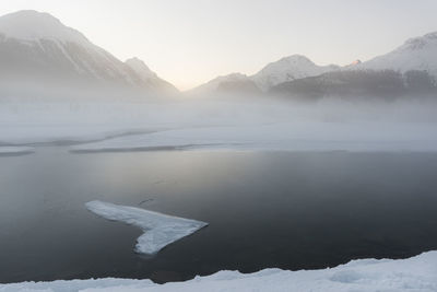 Scenic view of lake and snowcapped mountains against sky