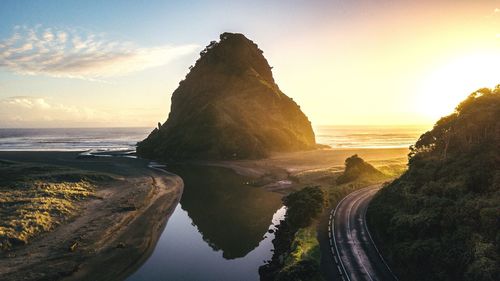 Rock formation on beach against sky during sunset