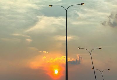 Low angle view of street lights against sky during sunset