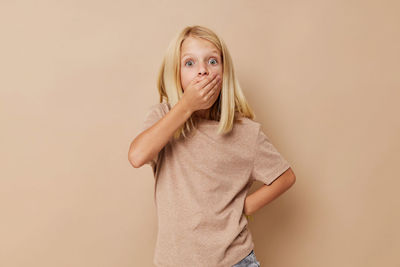 Portrait of young woman standing against pink background