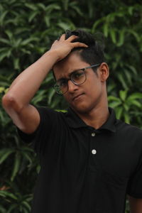 Portrait of young man standing against plants