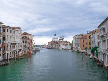 Canal amidst buildings in venice, italy against sky