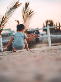 Asian kid paly sand at horse ranch while sunset.dramatic low key of simple life style of childhood.