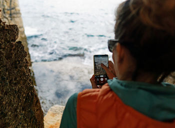 Rear view of person photographing on rock